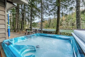 Ein Whirlpool inmitten eines bewaldeten Gebiets mit Blick auf einen Fluss und Berge im Hintergrund.