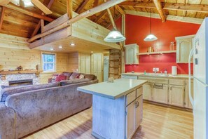 Ein Blockhaus-Interieur mit einer Couch, einer Küchenzeile und Holzbalken.
