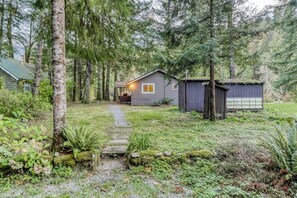 Eine Holzhütte mit einer Holzterrasse, umgeben von dichtem Wald.