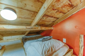 Ein Einzelbett in einem Zimmer mit Holzbalken und einer roten Wand.
