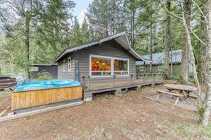 Een chalet met een jacuzzi, terras en picknicktafel, gelegen in een bebost gebied.
