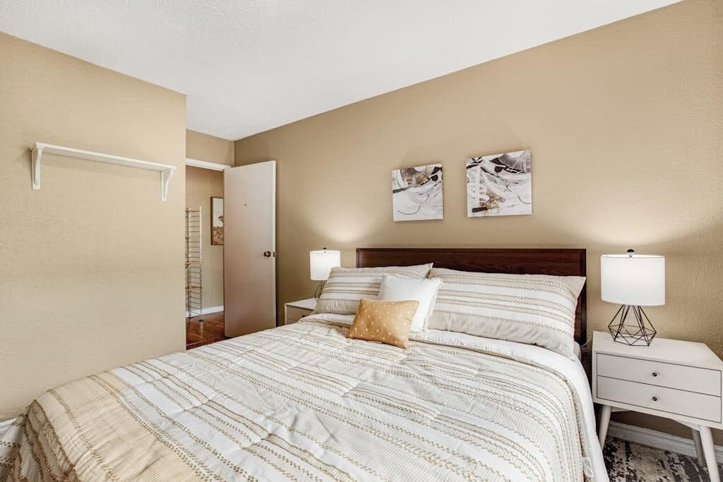 A bedroom with a bed, bedside tables, and wall art.
