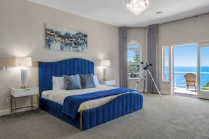 Quarto com cama grande, vista para o mar e varanda.