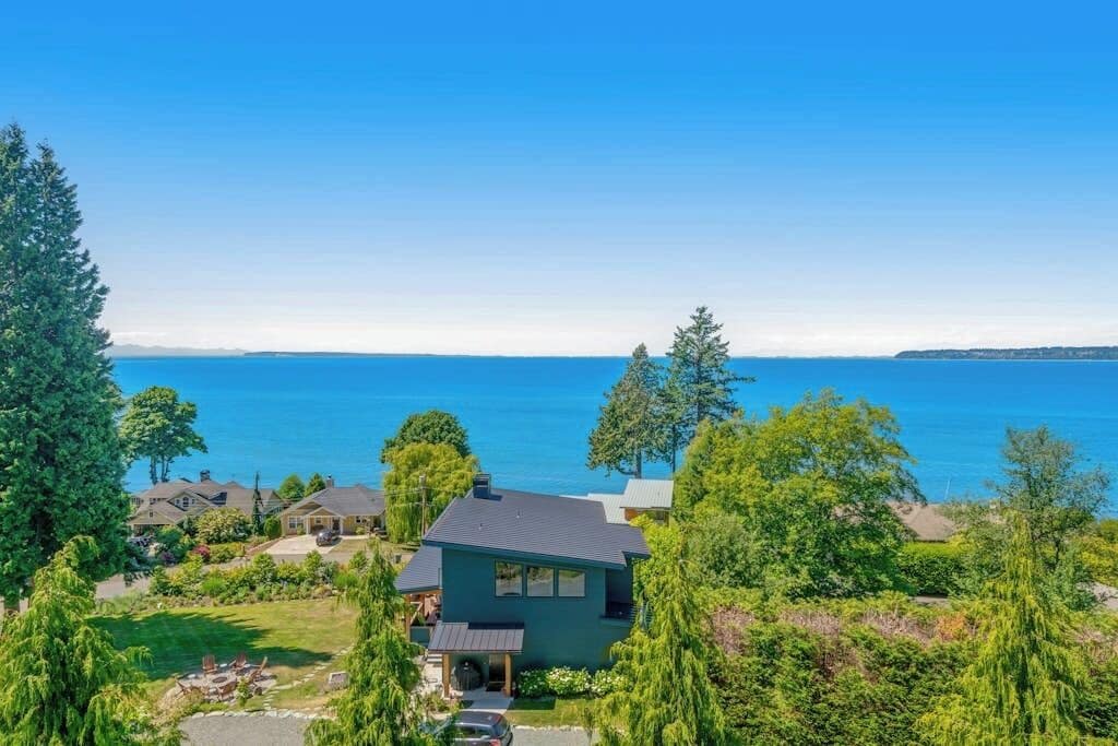A residential property with a view of a large body of water, surrounded by greenery and trees.