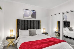 Ein Hotelzimmer mit Bett, Nachttischen, einem Spiegel und einem Bild an der Wand.