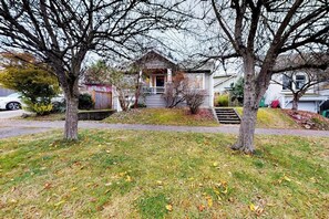 A residential house with a front porch, a small front yard, and a driveway. - Woodland 1BR - Patio - Washer Dryer (Seattle)