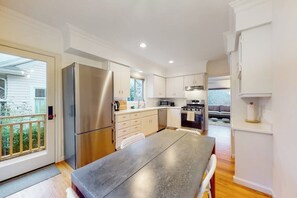 A modern kitchen with stainless steel appliances, a dining area with a wooden table, and a view of the outside. - Woodland 1BR - Patio - Washer Dryer (Seattle)