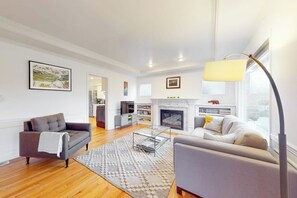 A modern living room with a fireplace, a sofa, a coffee table, and a lamp. - Woodland 1BR - Patio - Washer Dryer (Seattle)