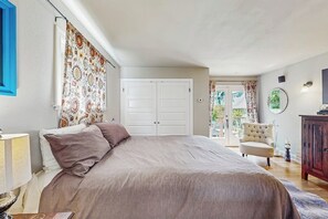 A bedroom with a bed, a wardrobe, a chair, and a door leading to a balcony. - 4BR Historic Home with Charm & Timeless Soul (Seattle)