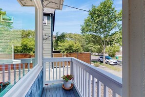 A balcony with a railing, a potted plant, and a view of a street with cars and trees. - 4BR Historic Home with Charm & Timeless Soul (Seattle)