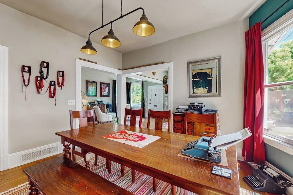 A dining area with a wooden table, chairs, and a vintage typewriter.