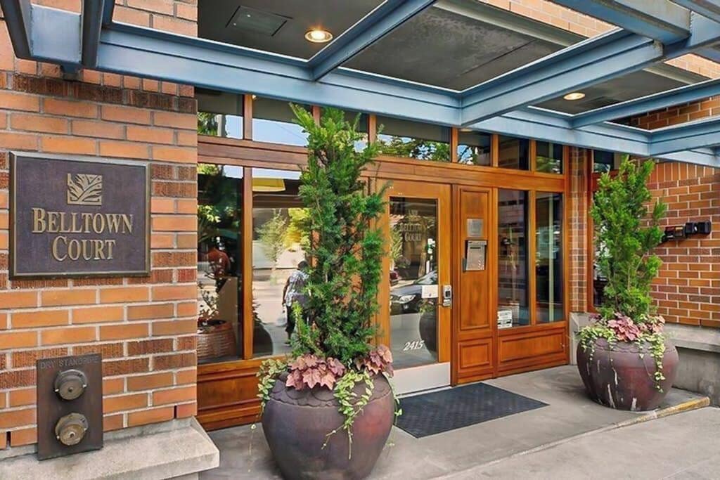 La entrada a Belltown Court, con fachada de ladrillo, puertas de vidrio grandes y dos plantas en macetas.