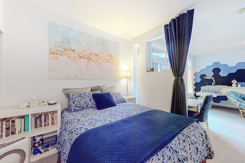 Een slaapkamer met een bed, een boekenkast, een bureau en een stoel.