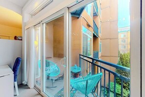 A balcony with a glass door, a table, and two chairs. - 1BR 5th-floor studio withheated pool, gym, hot tub (Seattle)