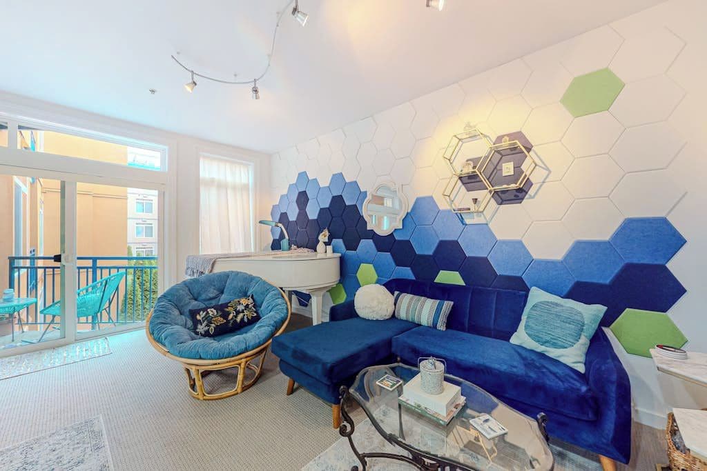 Una sala de estar moderna con un sofá azul, un sillón redondo y una mesa de centro de vidrio.