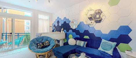 Una sala de estar moderna con un sofá azul, un sillón redondo y una mesa de centro de vidrio.