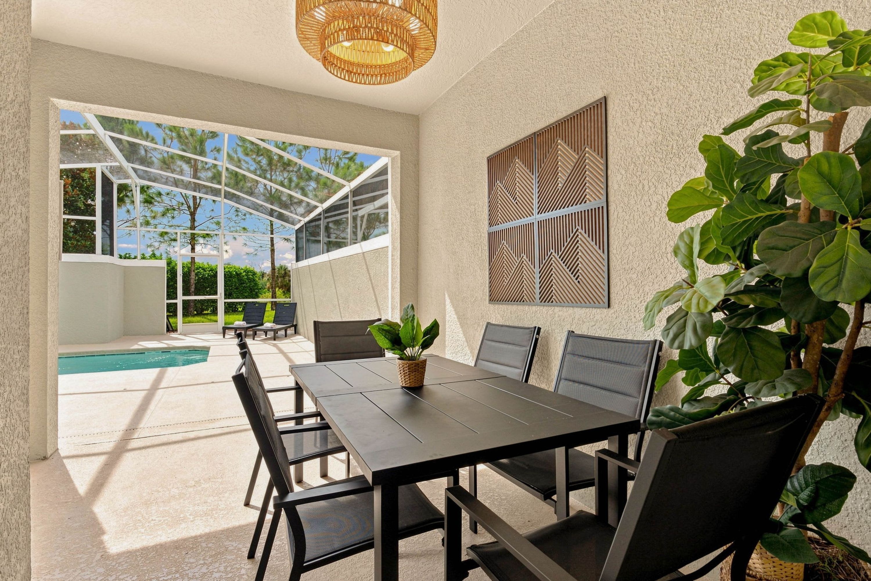 A modern outdoor dining area with a pool, large windows, and a view of the outdoors.