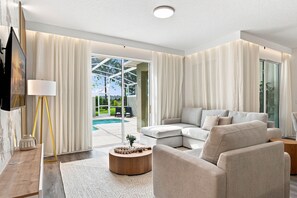 Una sala moderna con un sofá modular, una mesa de centro y un televisor montado en la pared.