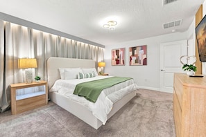 A bedroom with a bed, bedside tables, a lamp, curtains, a plant, and artwork on the walls. - Chic Disney Escape Themed Rooms Private Pool (Davenport)