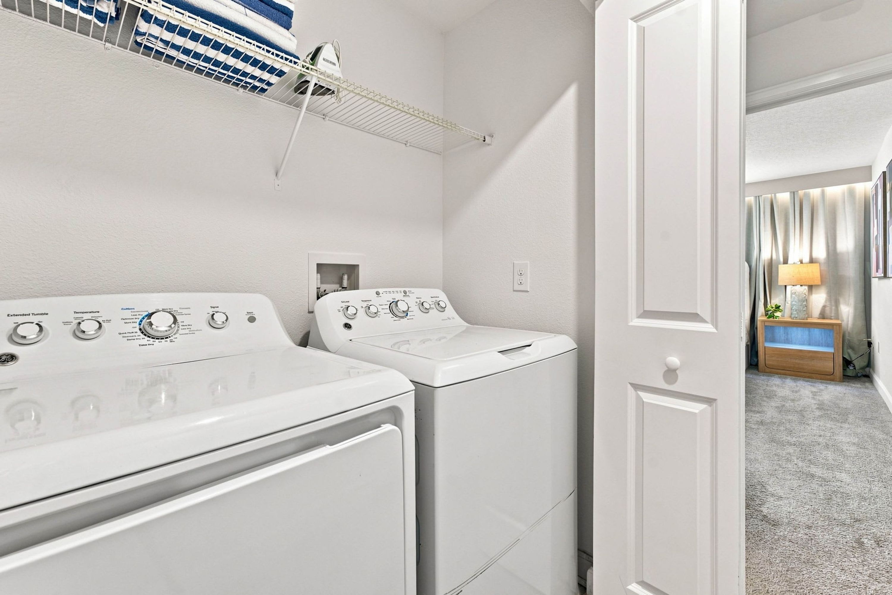 A laundry area with two white washing machines and a drying rack.