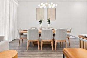 A modern dining area with a round wooden table, six grey upholstered chairs, and two wall-mounted light fixtures. - Chic Disney Escape Themed Rooms Private Pool (Davenport)