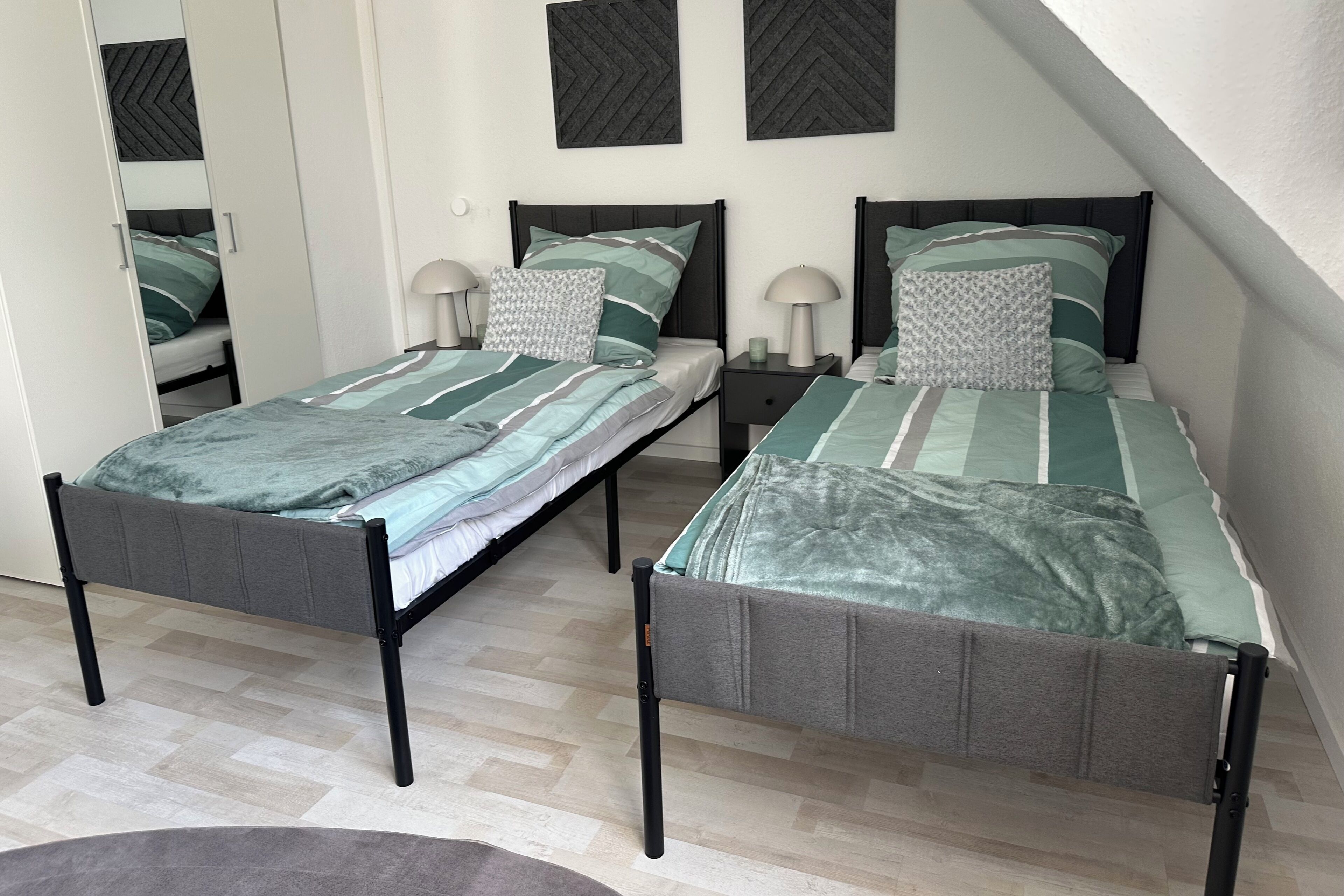 Ein Schlafzimmer mit zwei Einzelbetten, einem Nachttisch mit Lampe und einem Spiegel an der Wand.