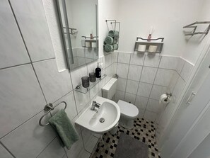 Un baño pequeño con lavamanos, inodoro y espejo sobre el lavamanos.