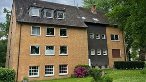 Un immeuble résidentiel à deux étages, doté de nombreuses fenêtres, d’une façade en briques et d’une pelouse bien entretenue.