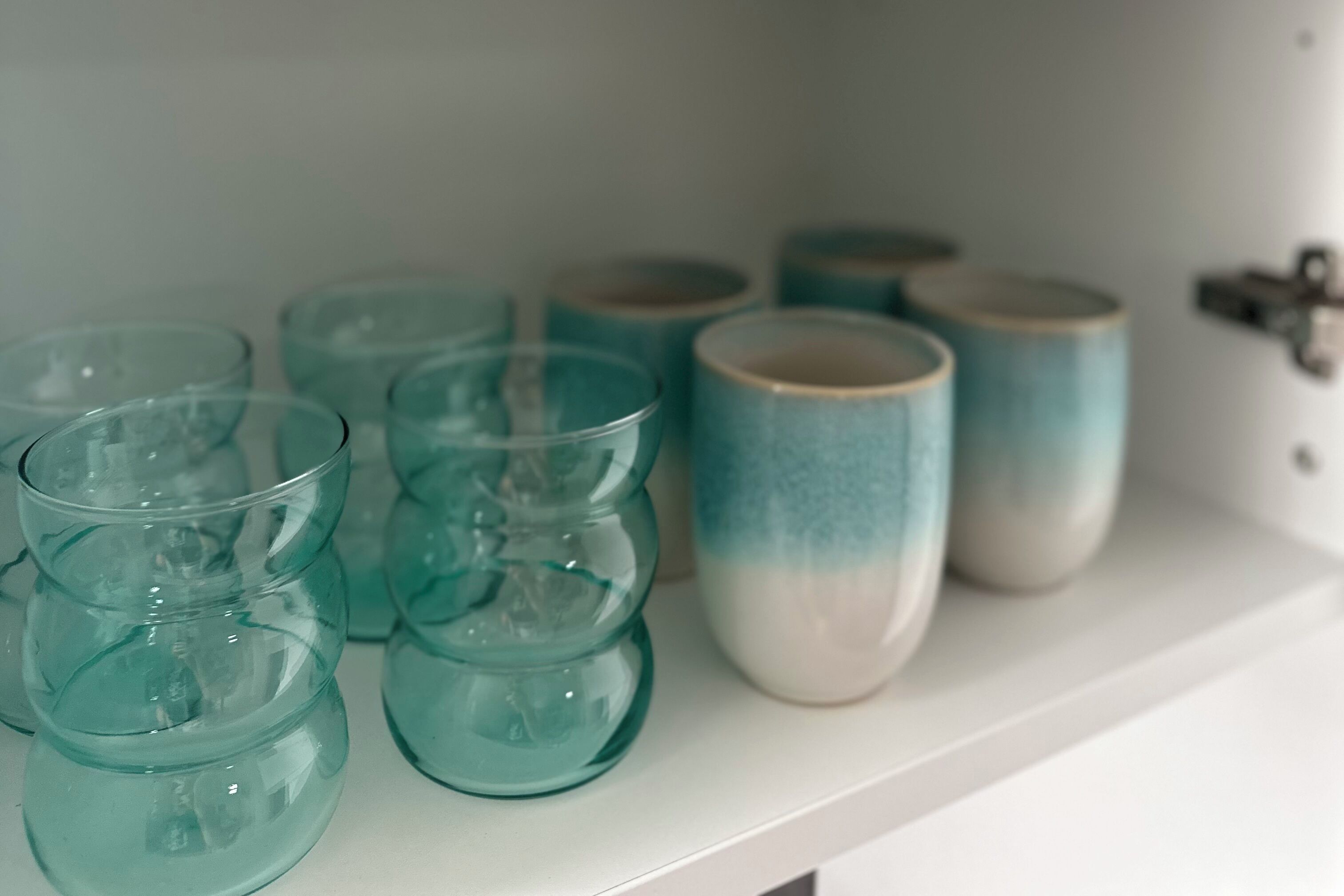 Ein Regal mit verschiedenen Glasbehältern und Keramiktassen.