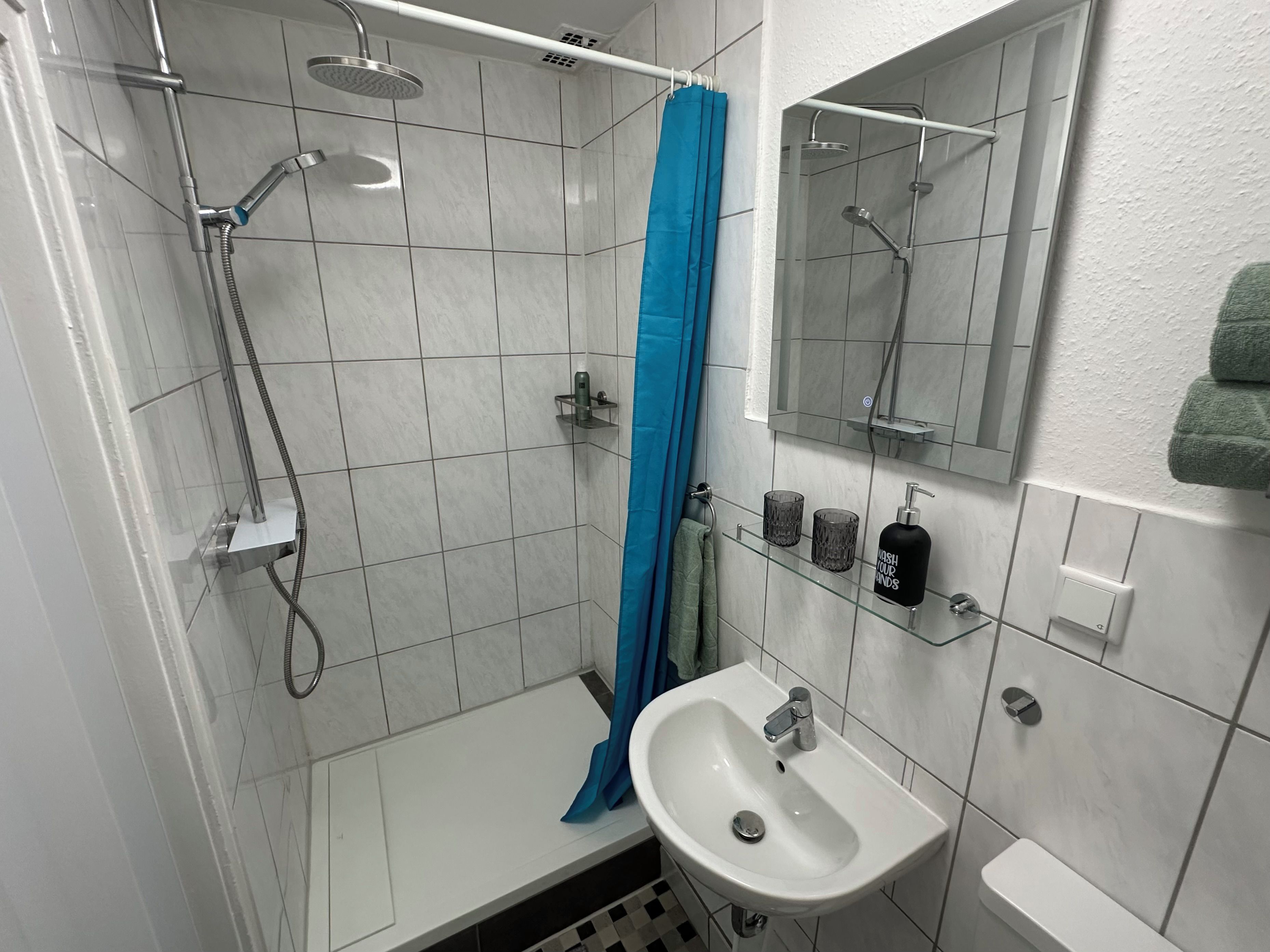Ein Badezimmer mit Dusche, Waschbecken und Spiegel.