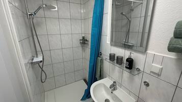 Ein Badezimmer mit Dusche, Waschbecken und Spiegel.
