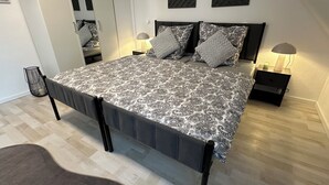 Une chambre à coucher avec un lit, des tables de chevet et un miroir.