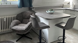 Une cuisine moderne avec un îlot central, des tabourets de bar et une chaise.