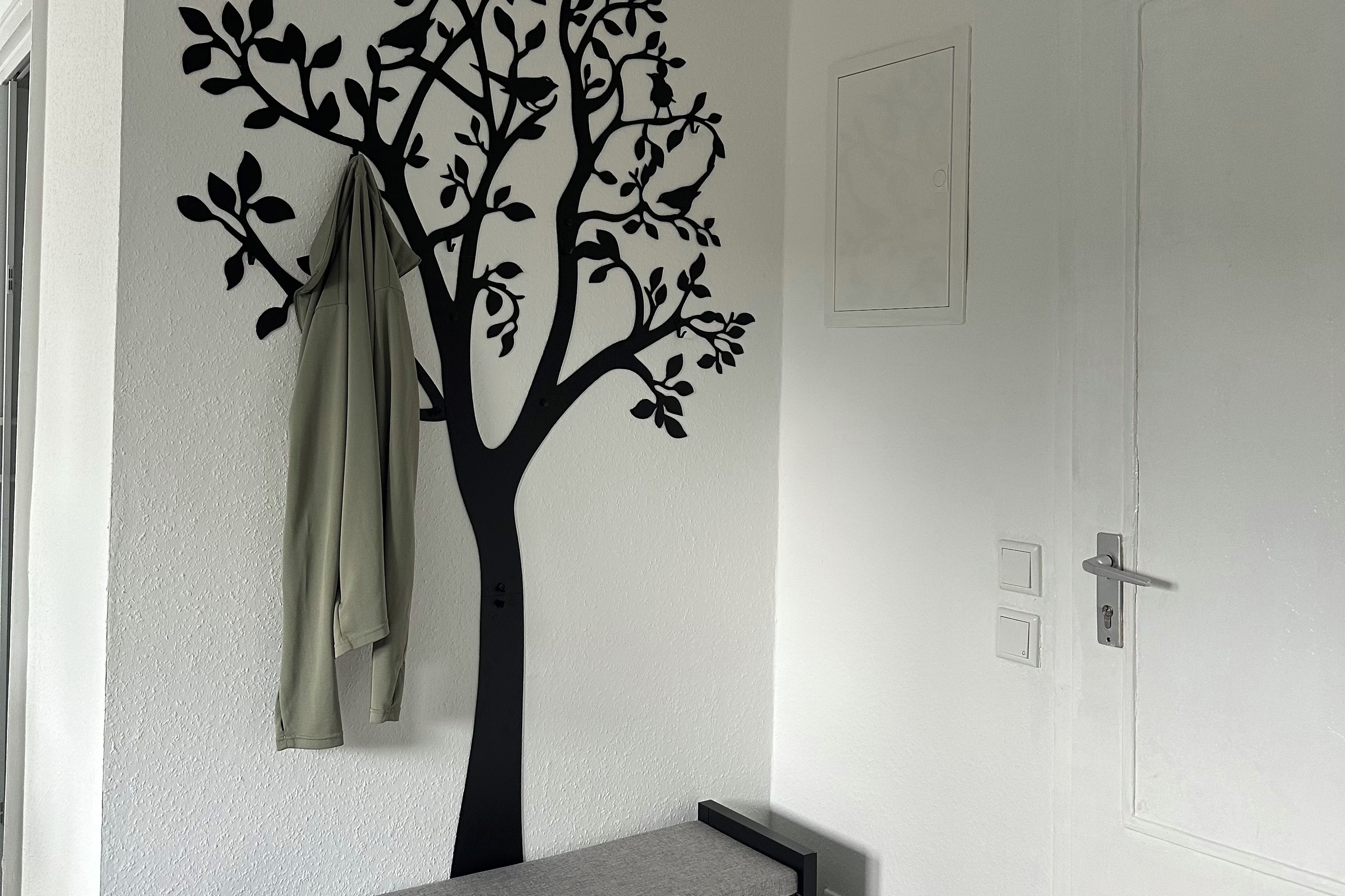 Ein Zimmer mit einer Wanddekoration in Form eines Baumes, einer Tür mit Griff und einem Lichtschalter.
