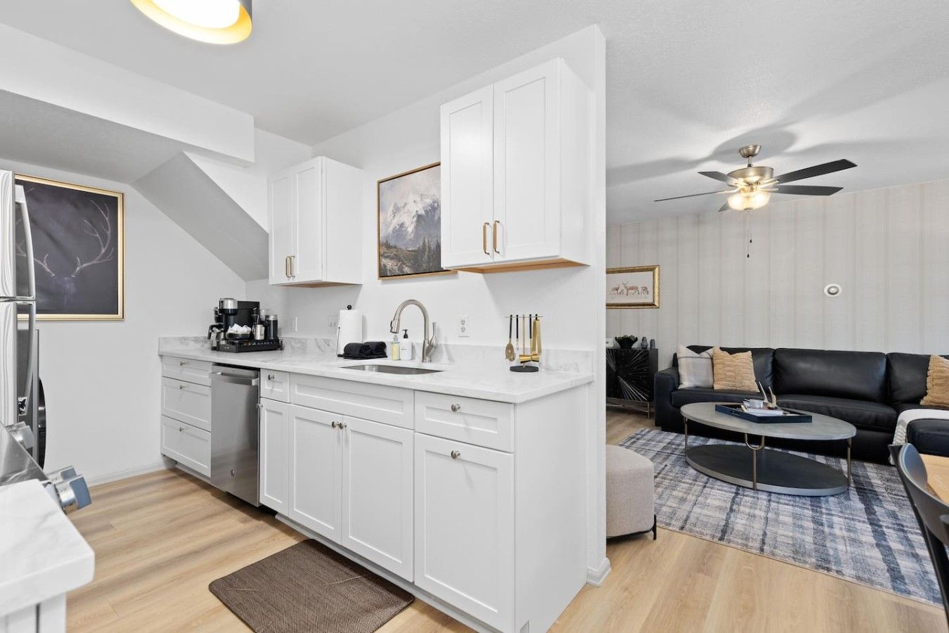 A modern kitchen with white cabinetry, a built-in dishwasher, and a central island with a sink.