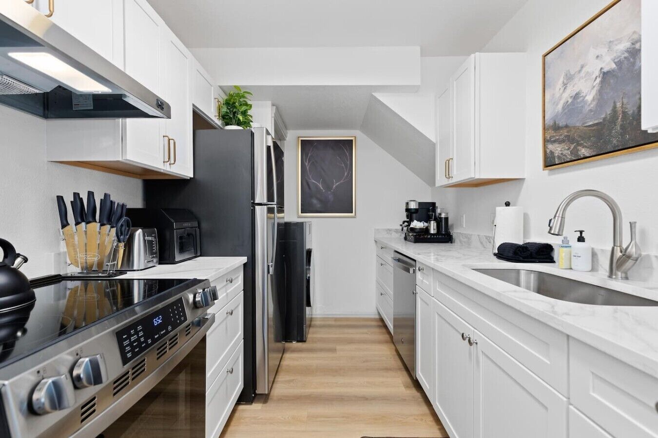 A modern kitchen with white cabinets, stainless steel appliances, and a marble countertop.