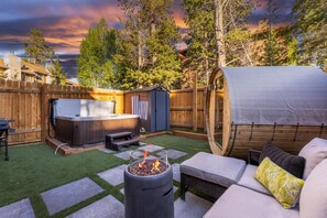 Un jardin avec un jacuzzi, un espace salon couvert et un foyer extérieur.