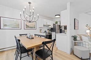 A modern kitchen with white cabinetry, a dining table with chairs, and a chandelier. - Frisco Retreat W/ Hot Tub, Sauna, Dog Friendly (Frisco)