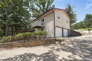 Ein zweigeschossiges Gebäude mit Balkon, Garage und einer Steinmauer.