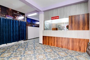 Zona de recepción de un hotel con mostrador, cartel de recepción y suelo estampado.
