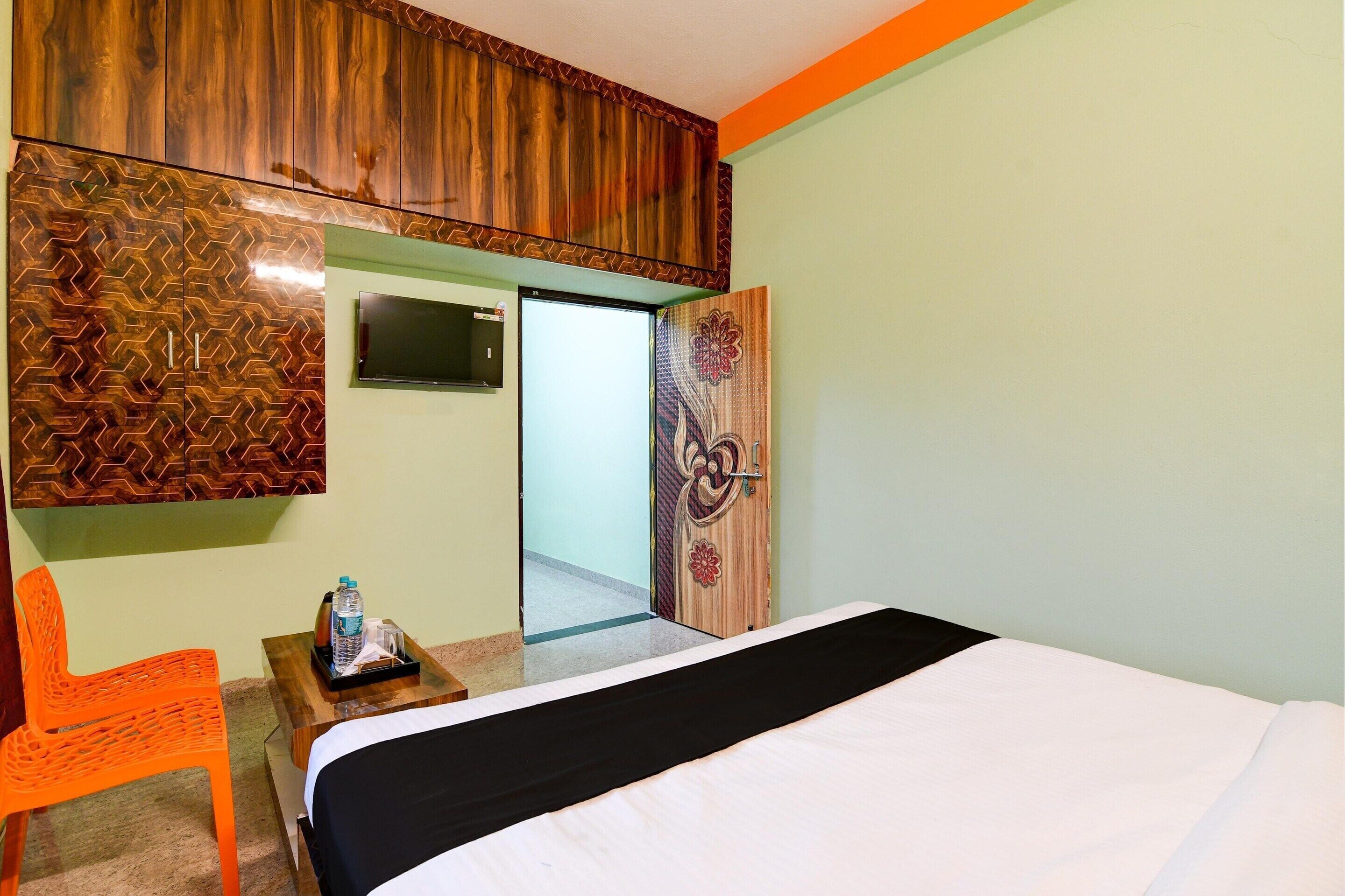 Una habitación de hotel con una cama, un televisor, una puerta de madera con diseño floral y una silla.