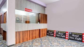 Un mostrador de recepción con un cartel que dice 'RECEPTION', una barra de madera y un suelo de baldosas con un diseño circular.