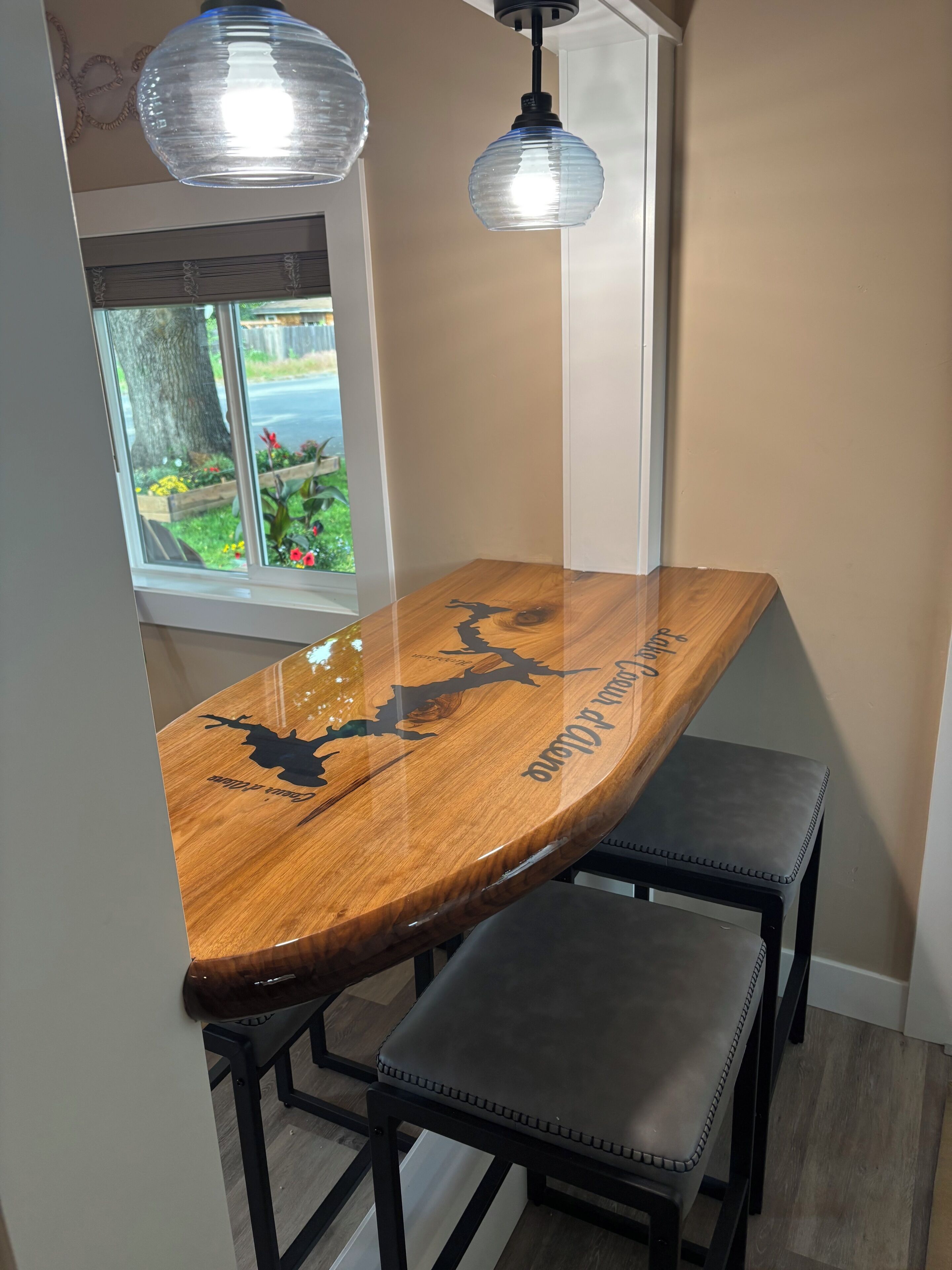 A corner dining area with a wooden table and two black metal chairs.