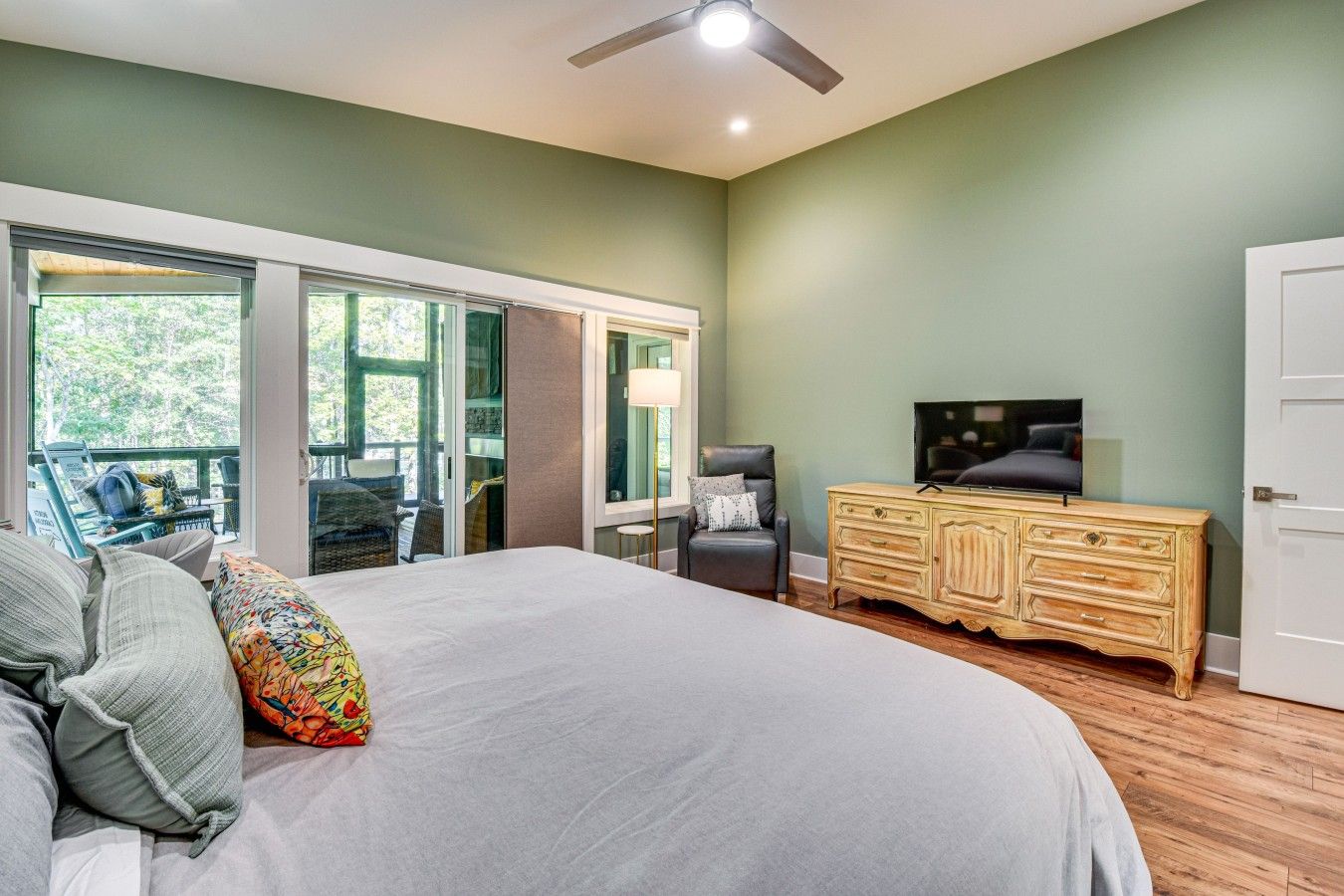 Quarto com cama grande, televisão, penteadeira de madeira e uma cadeira.