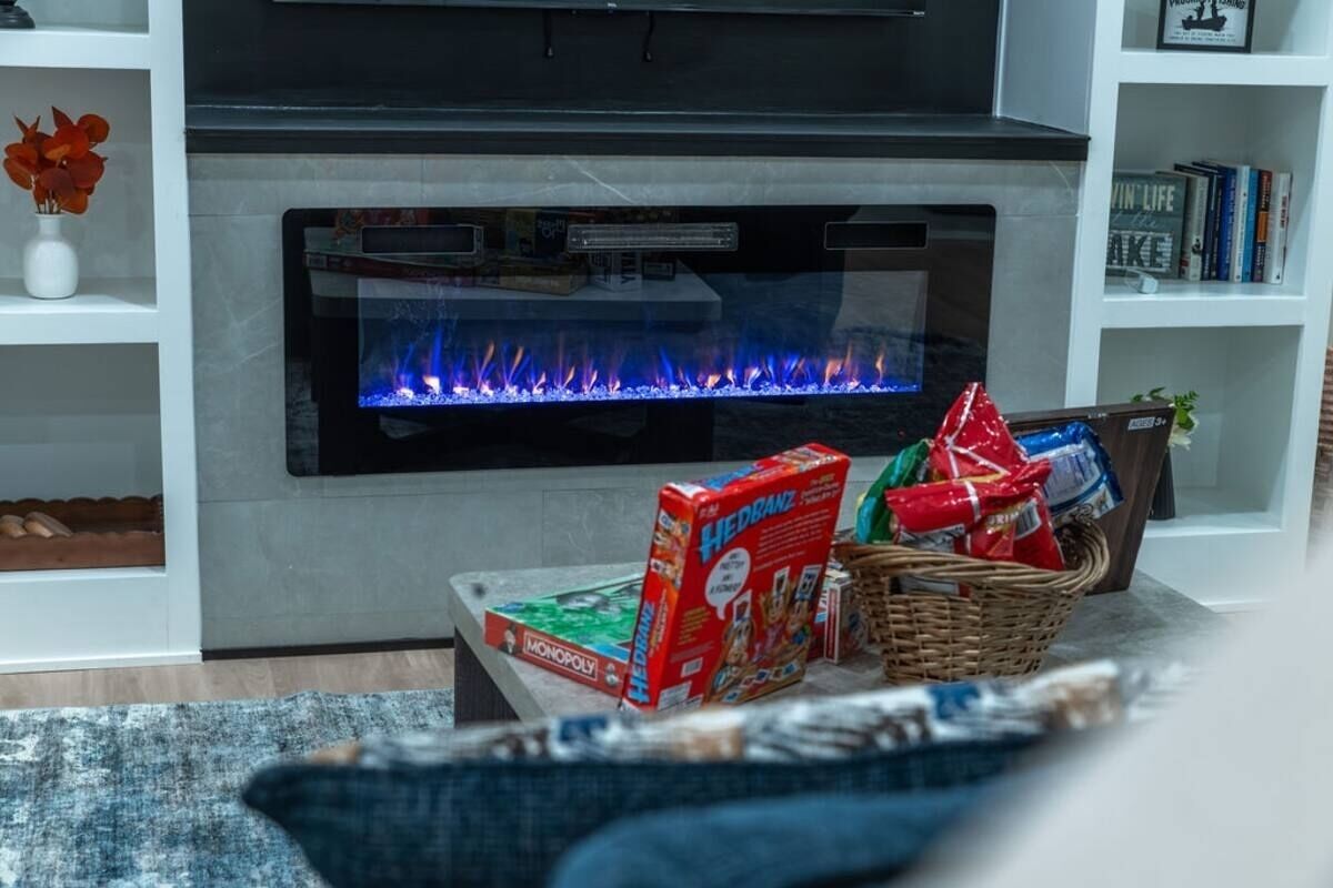 Ein Wohnzimmer mit modernem Kamin, Fernseher und Bücherregal.