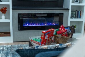 Ein Wohnzimmer mit modernem Kamin, Fernseher und Bücherregal.
