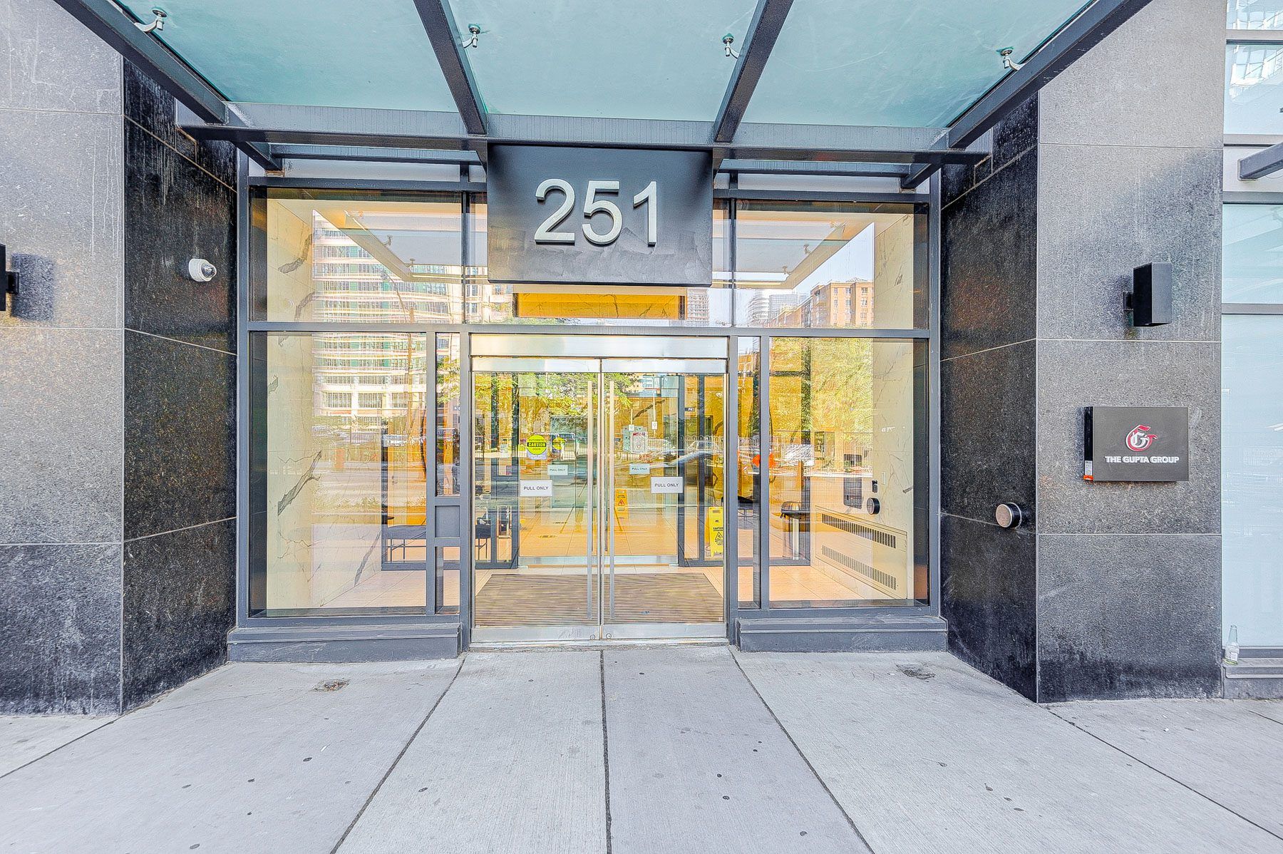 A modern building entrance with a glass door marked '251' and a sign for 'The Guitta Group'.