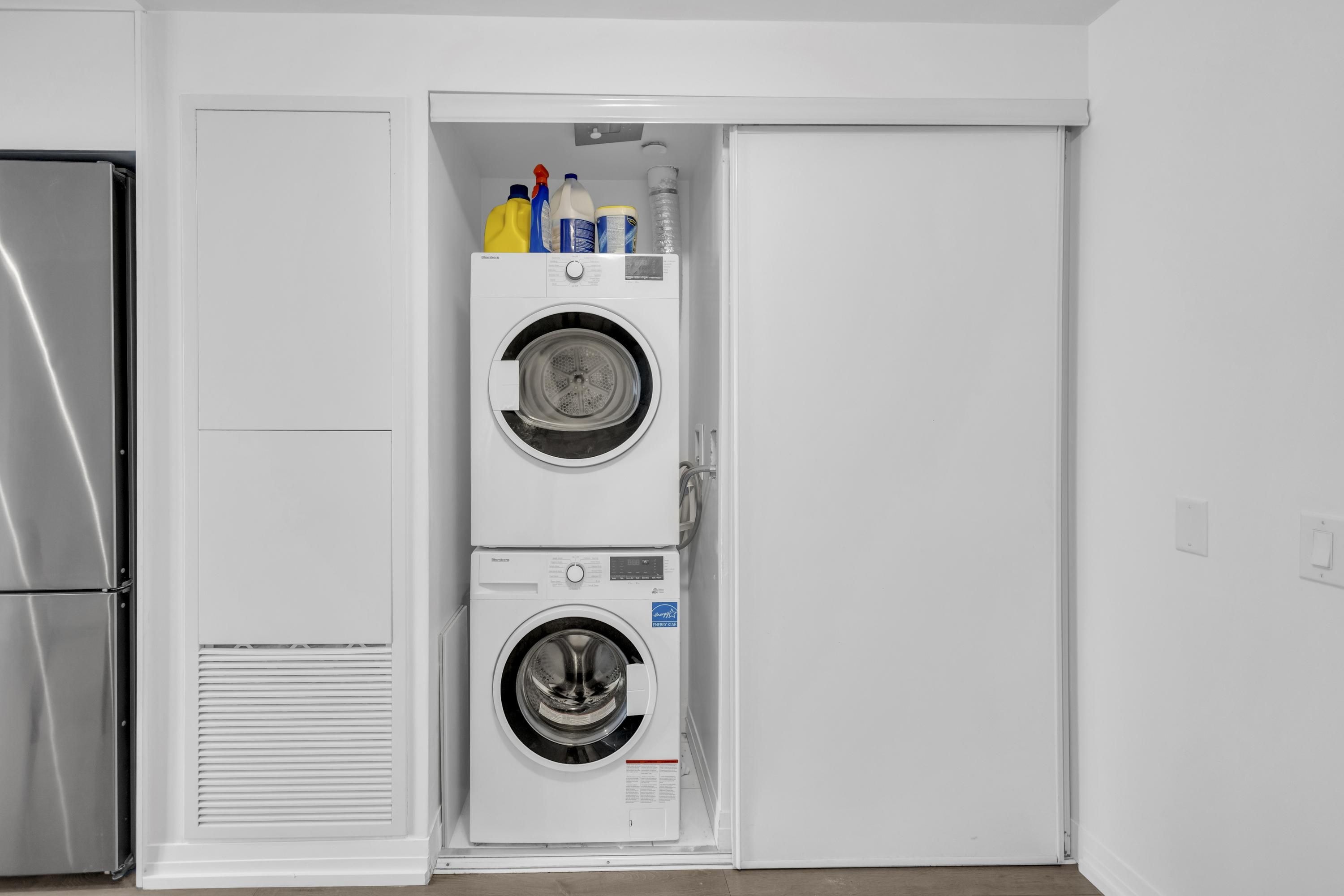 A compact laundry room with two stacked washing machines and a refrigerator.