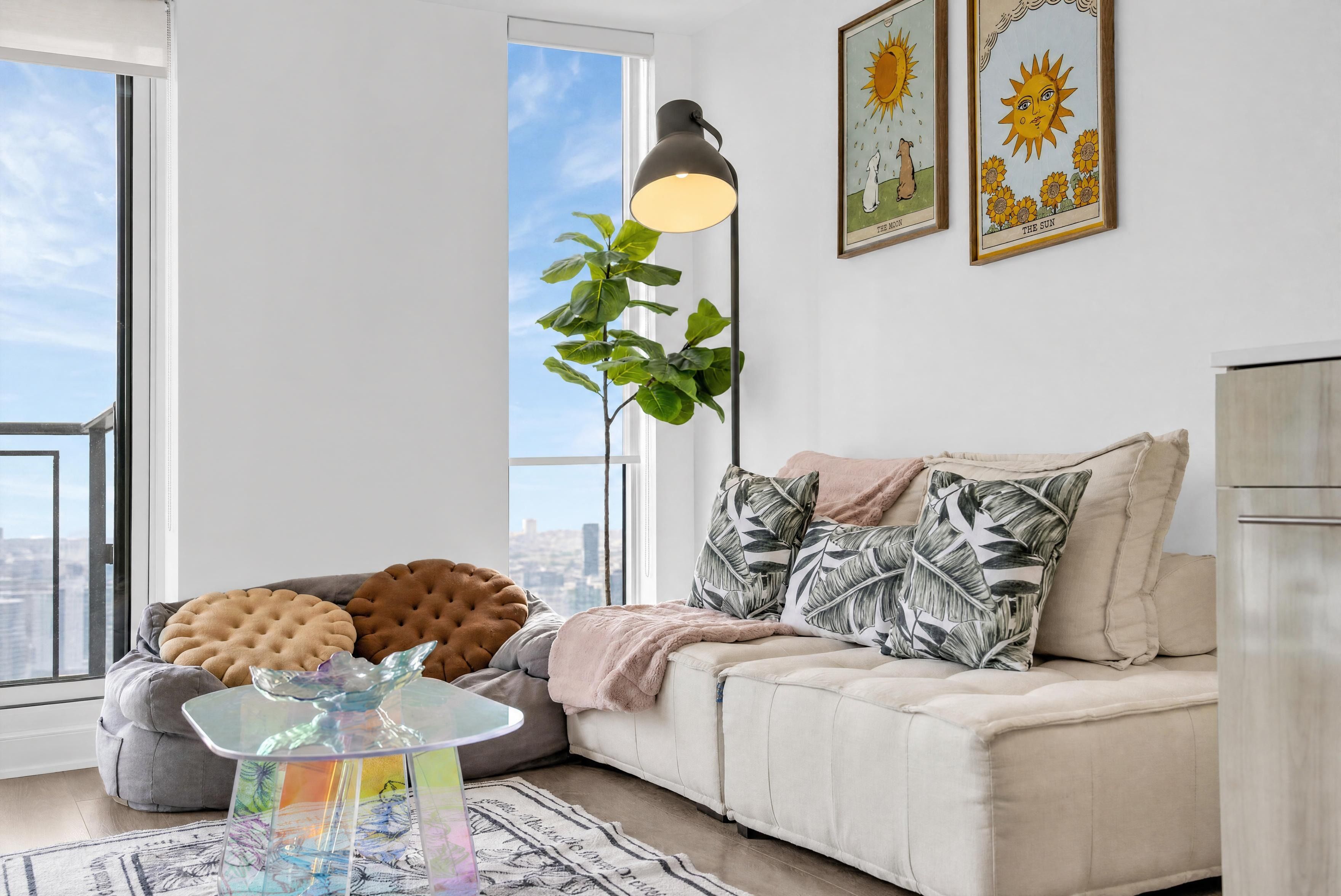 A modern living room with a sofa, cushions, a glass coffee table, and a floor lamp.