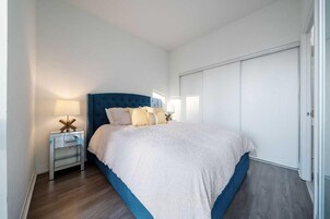 Een slaapkamer met een bed, nachtkastjes, een lamp en een kledingkast.